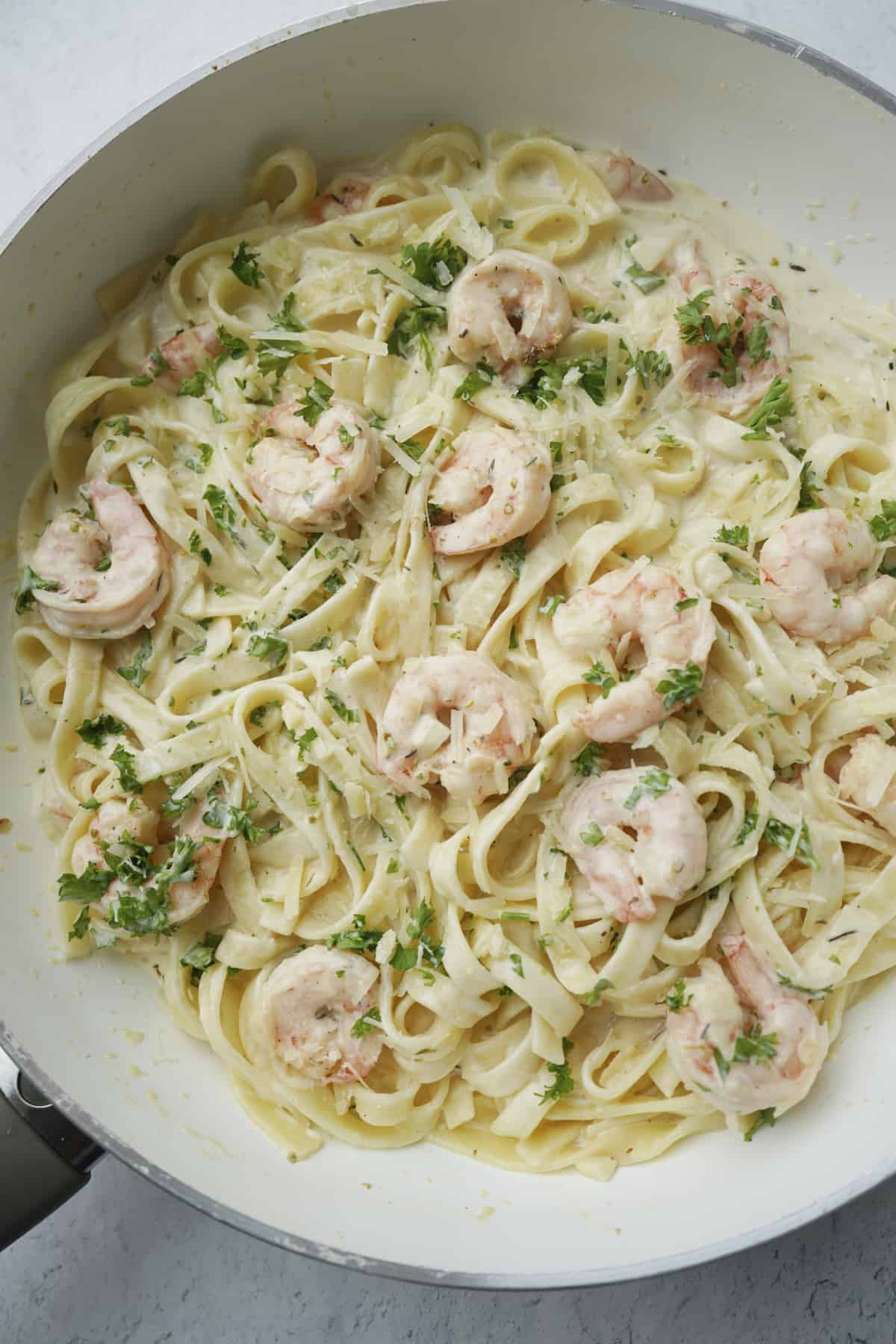 overhead of shrimp linguine with fresh parsley in a pan