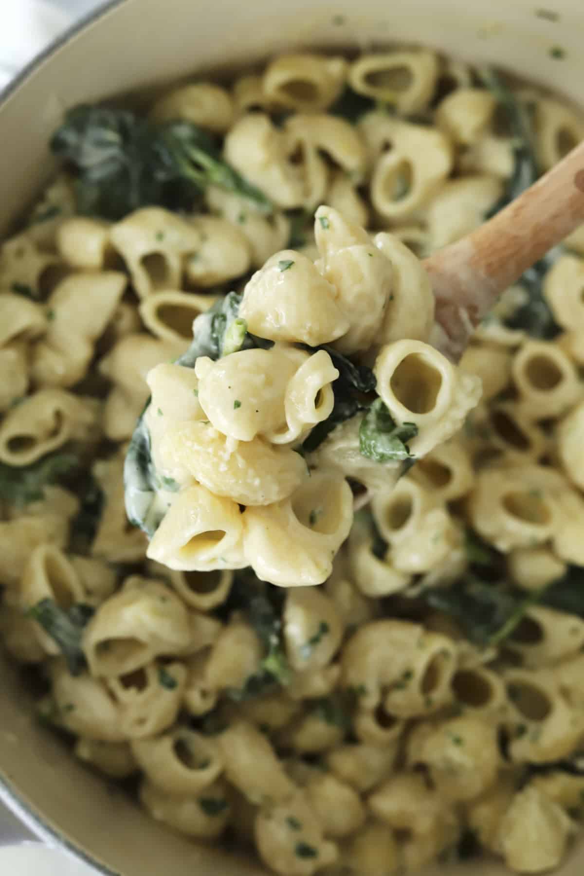 a spoon lifting a scoop of lemon garlic pasta from a pot