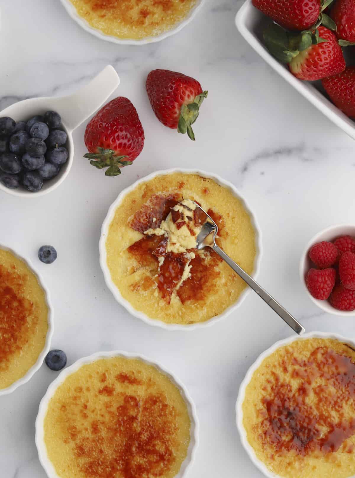 creme brûlée ramekins with a spoon dipping into one