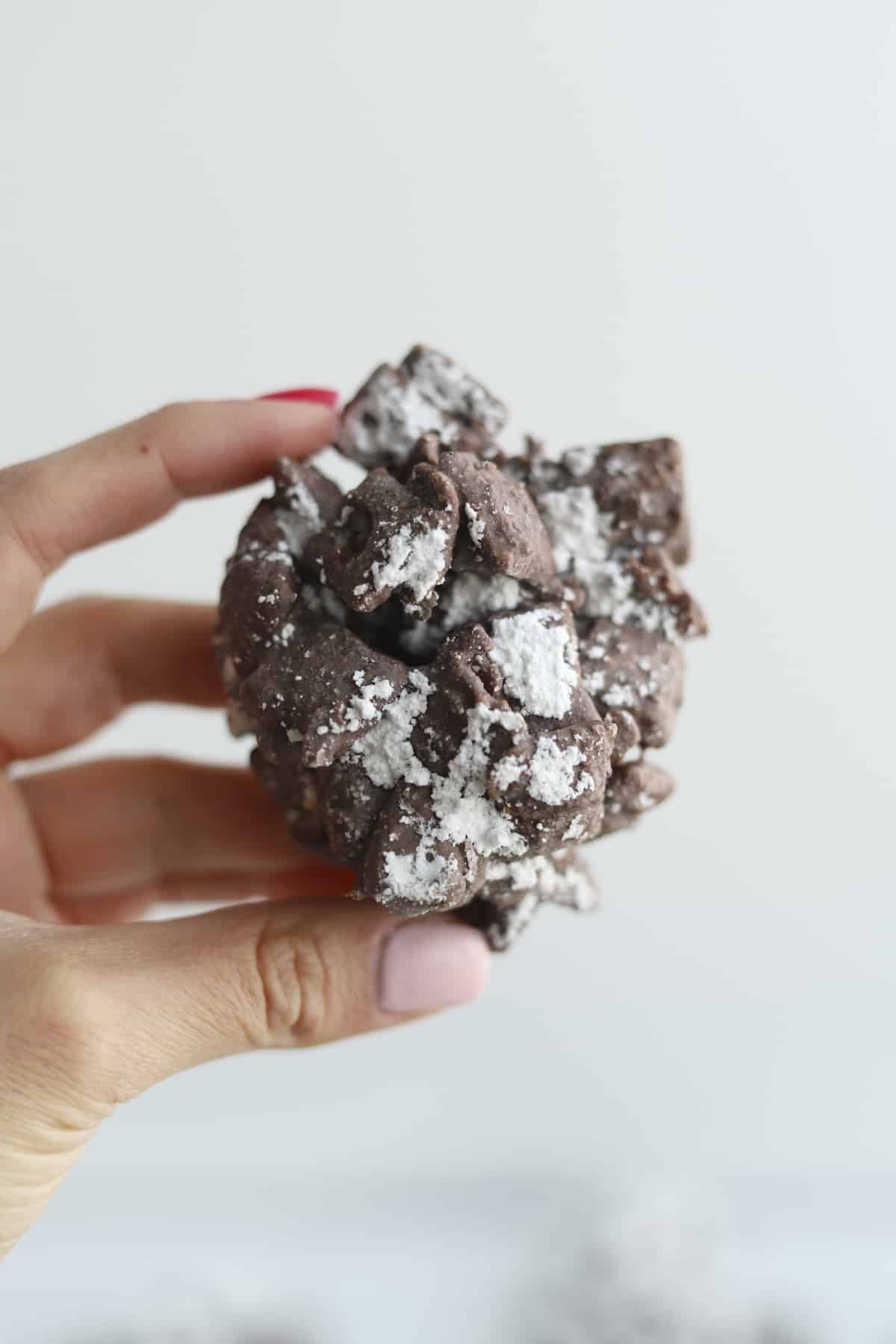a hand holding a chunk of slow cooker puppy chow
