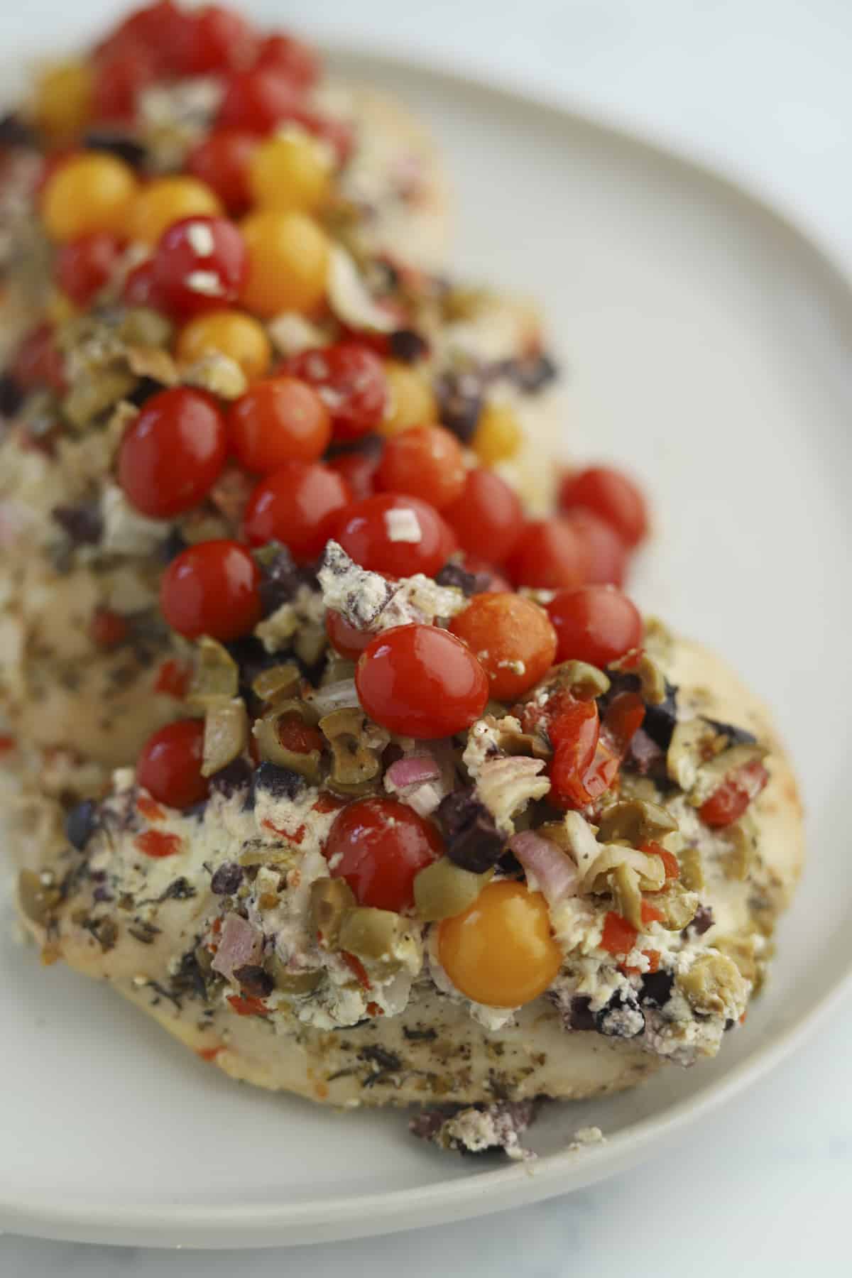 plated whipped feta baking chicken with tomatoes and olives.