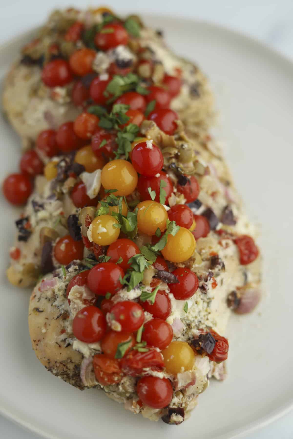 closeup of chicken topped with whipped feta and baby tomatoes