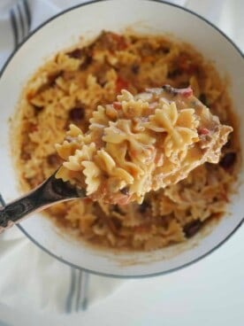 a serving spoon scooping up chili mac and cheese from a pot