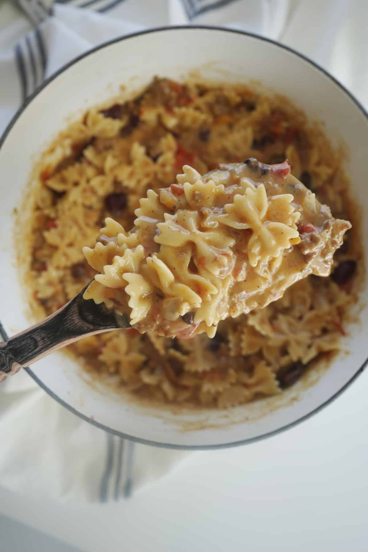 a spoon scooping up chili mac and cheese from a pot