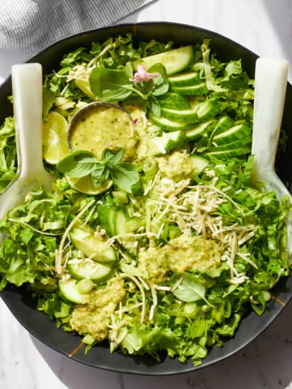 A bowl of green goddess dressing topped with green goddess salad.