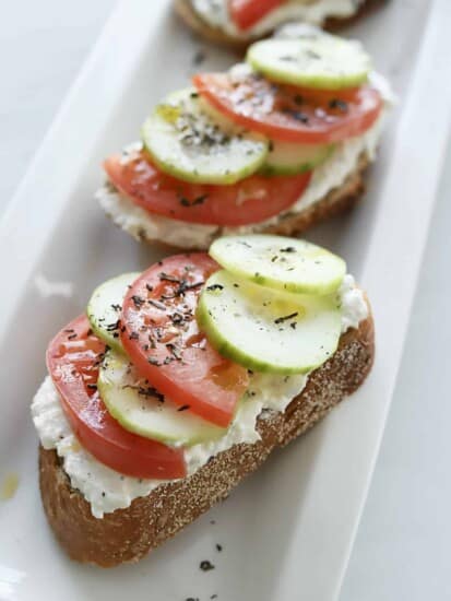 sideview of feta toast with tomatoes and cucumbers