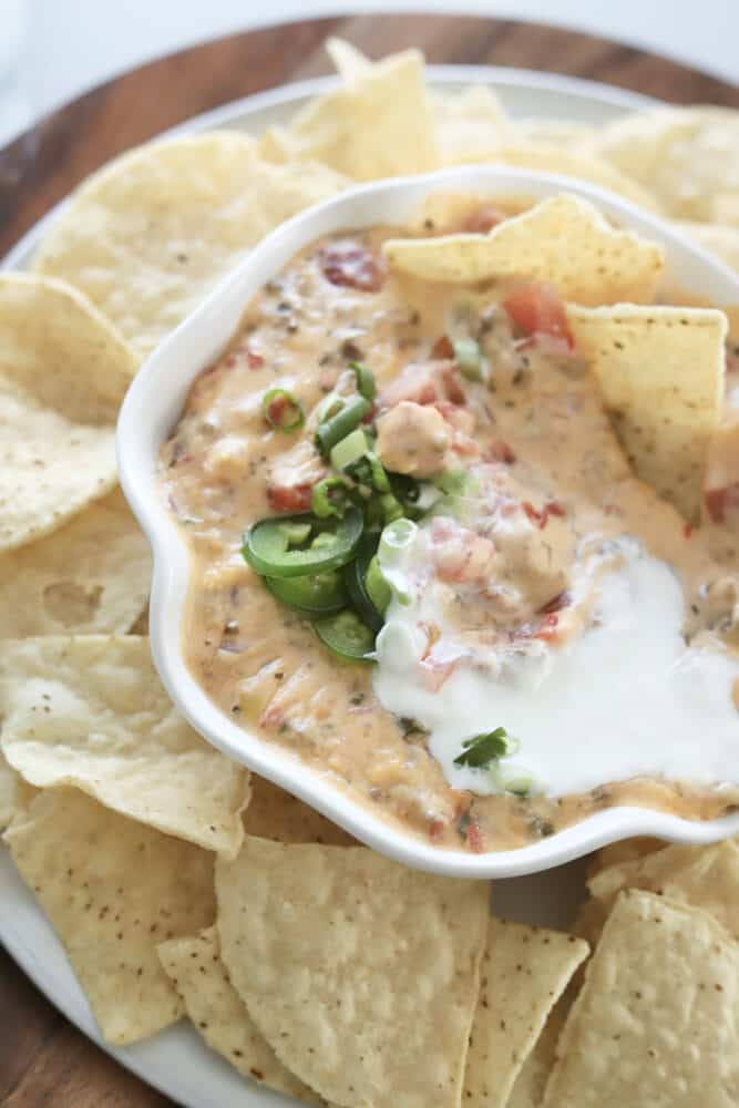 overhead image of baked queso in a white bowl surrounded by tortilla chips
