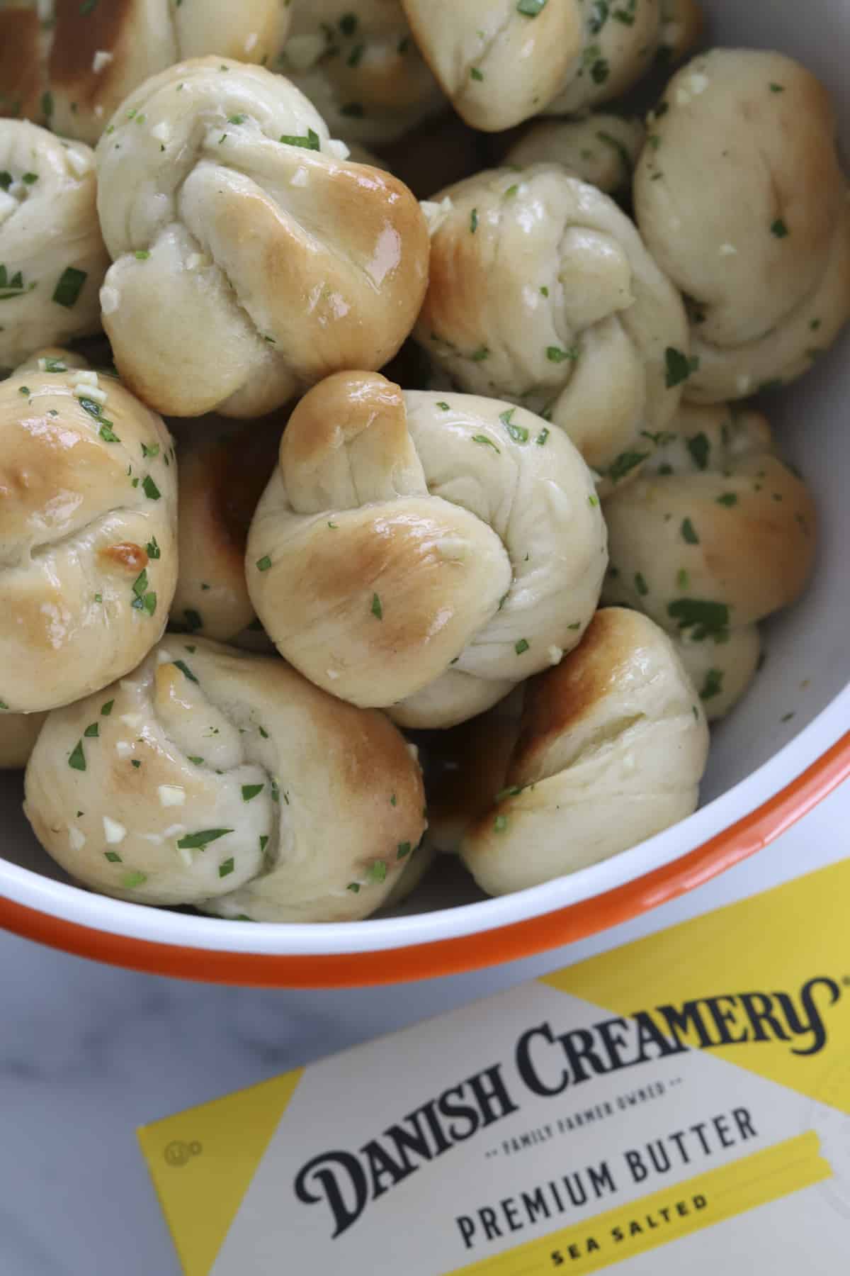 cheesy garlic knots in a bowl with butter