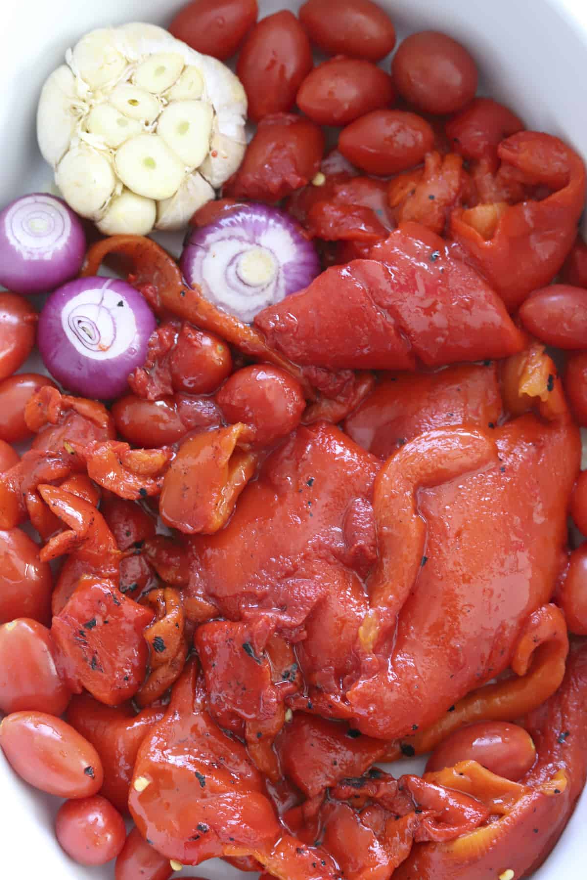 overhead baking dish with roasted peppers, tomatoes, and garlic