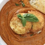 overhead image of a bowl of fried burrata with romesco sauce with a piece of bread dipped in