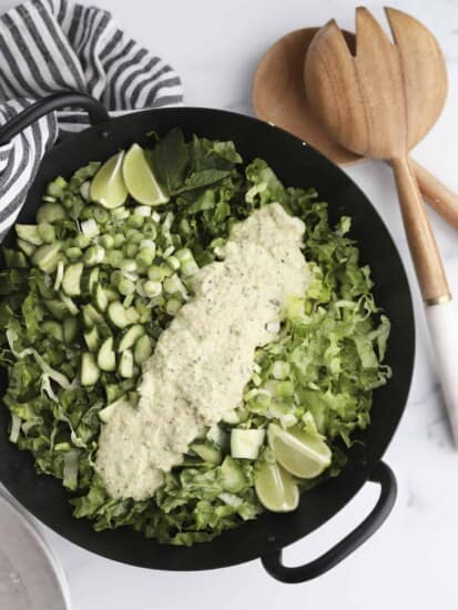 A bowl of green goddess salad topped with green goddess dressing.