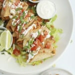 overhead of mini air fryer taquitos with tomatoes, sour cream, and green onions