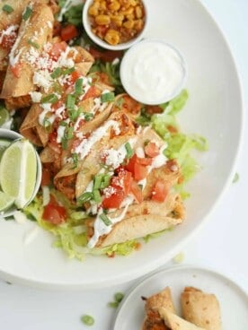 overhead of mini air fryer taquitos with tomatoes, sour cream, and green onions