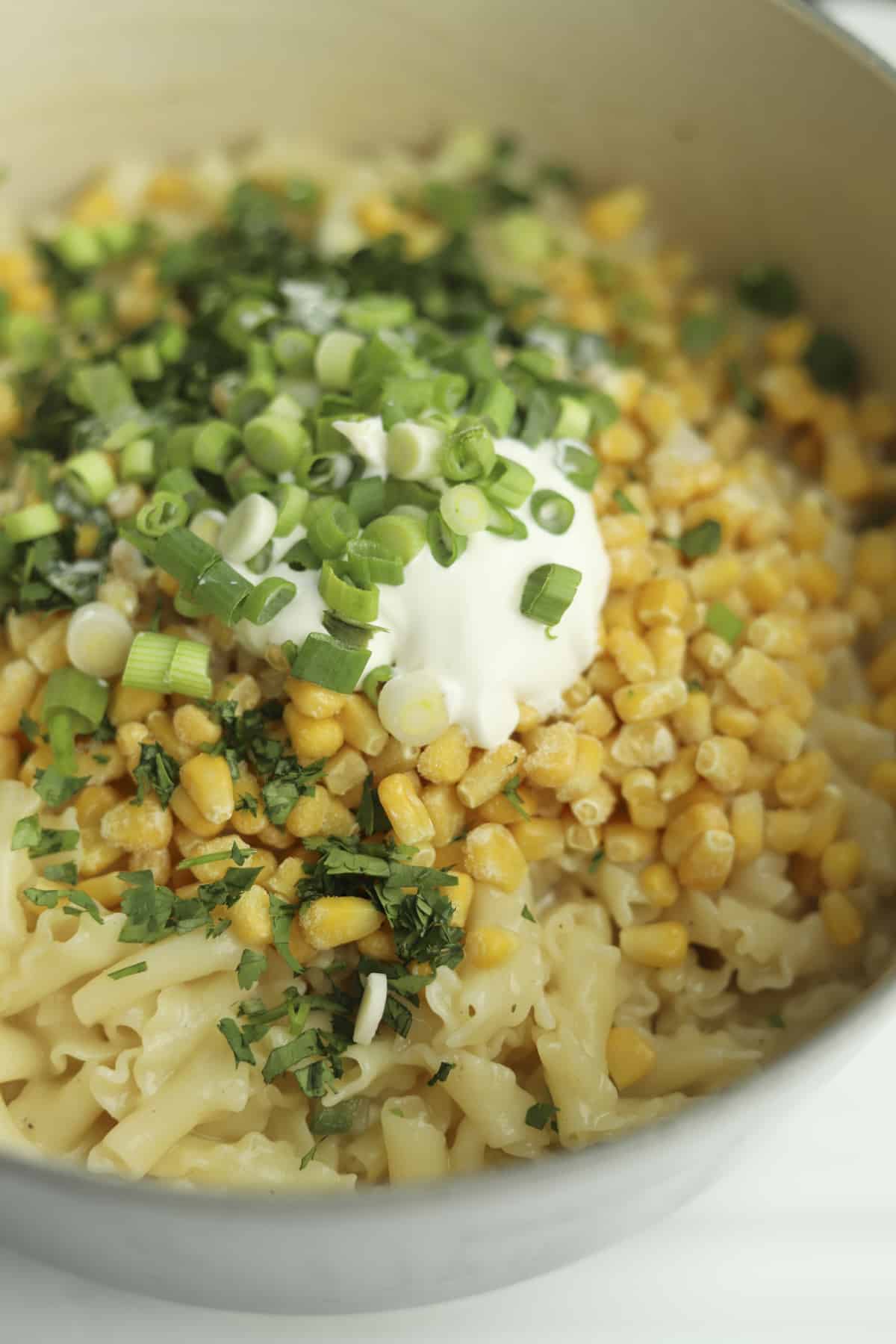 pasta topped with corn, fresh herbs, sour cream, and green onions