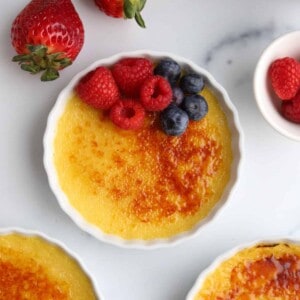 ramekins of creme brulee topped with raspberries and blueberries