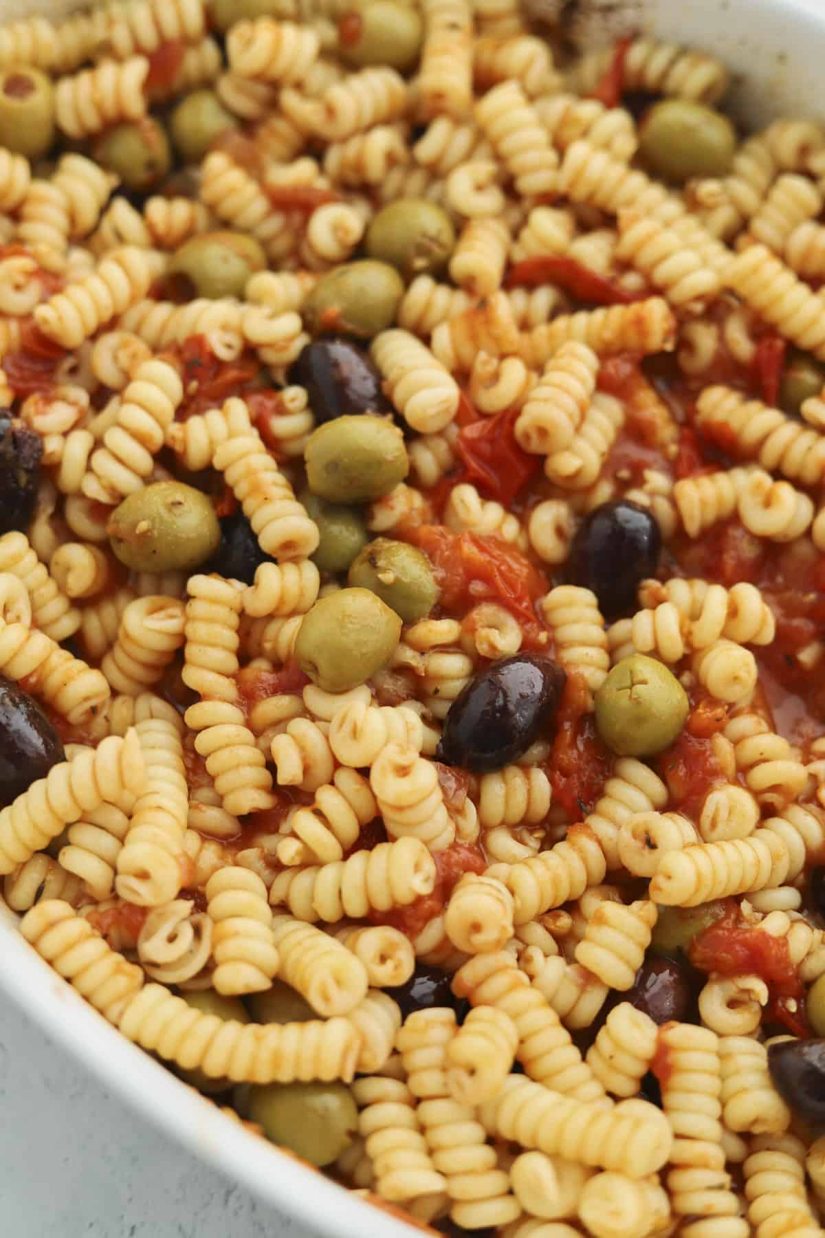 overhead of pasta in a baking dish with olives and tomatoes