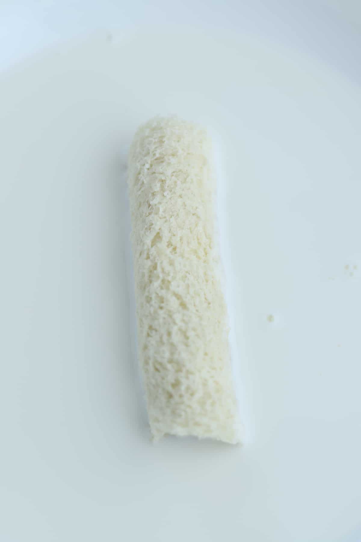 a rolled up piece of bread in a milk mixture