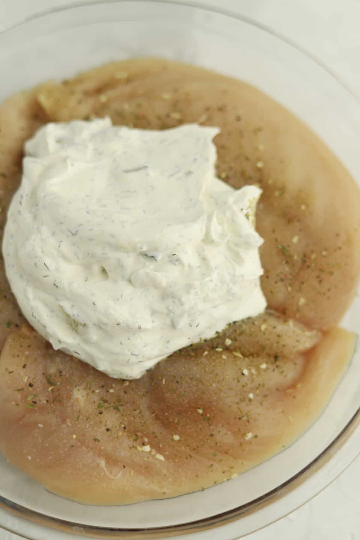 raw chicken in a bowl topped with  tzatziki