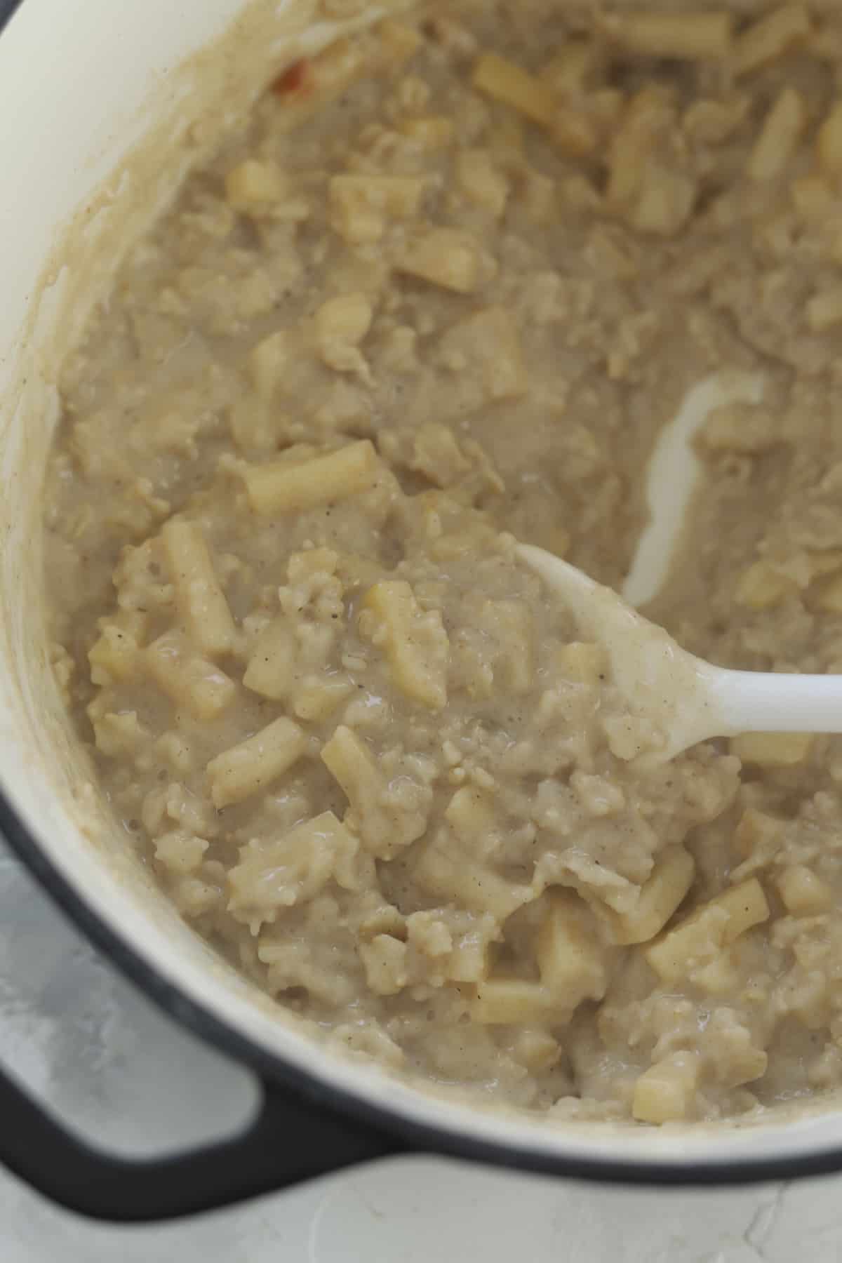a spoon stirring apple cinnamon oats in a pot