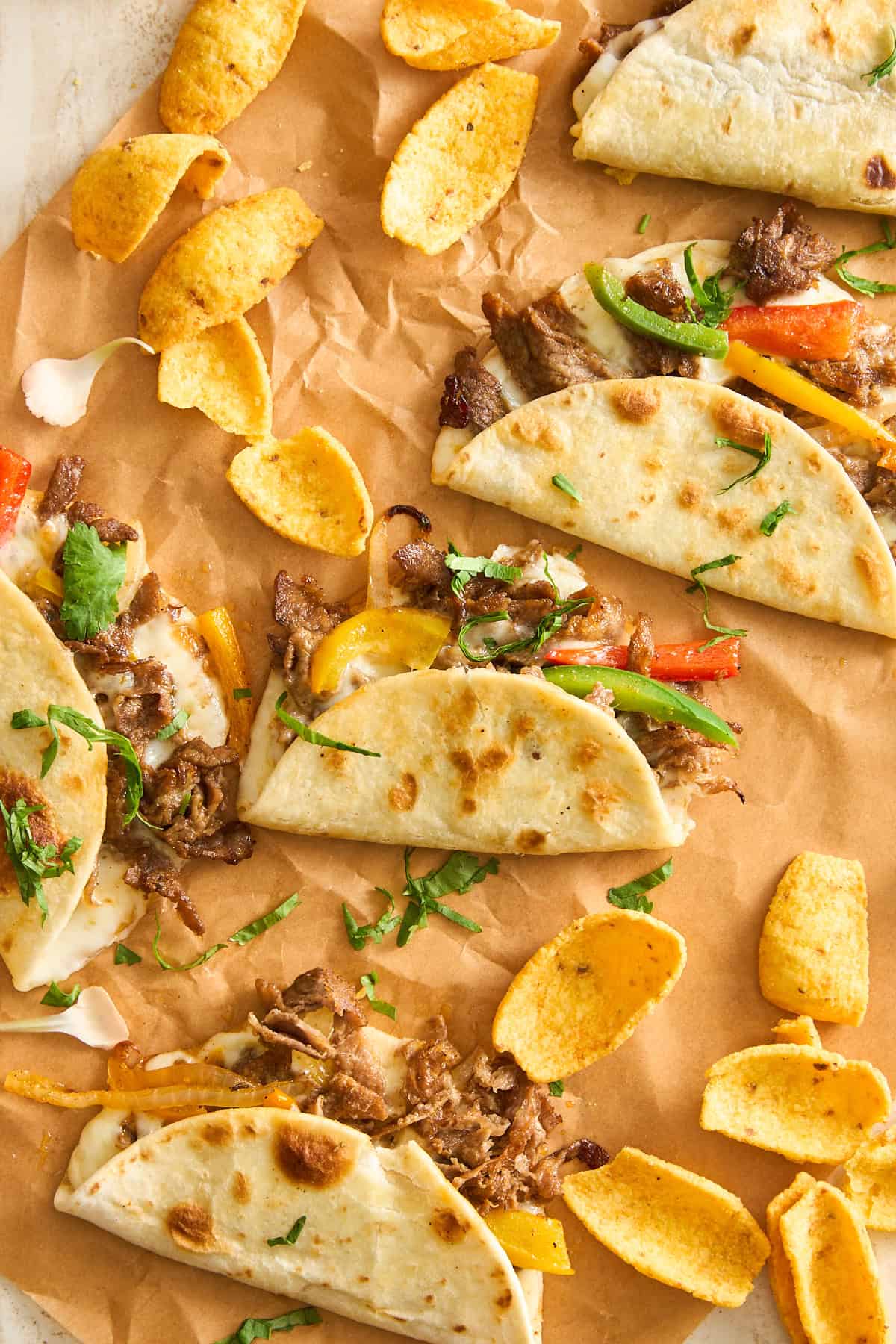 A group of Philly cheesesteak tacos on a paper.