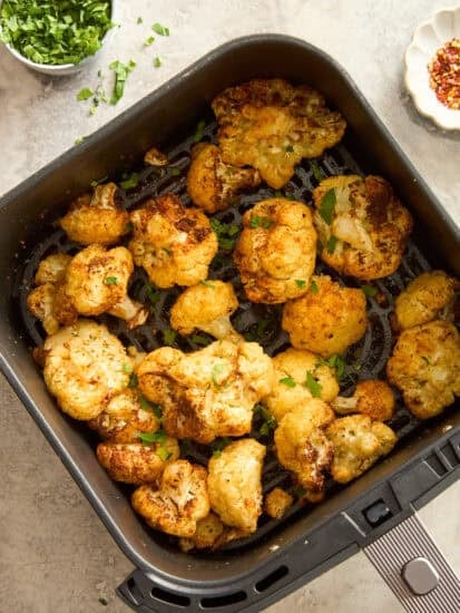 Roasted air fryer cauliflower in an air fryer basket.