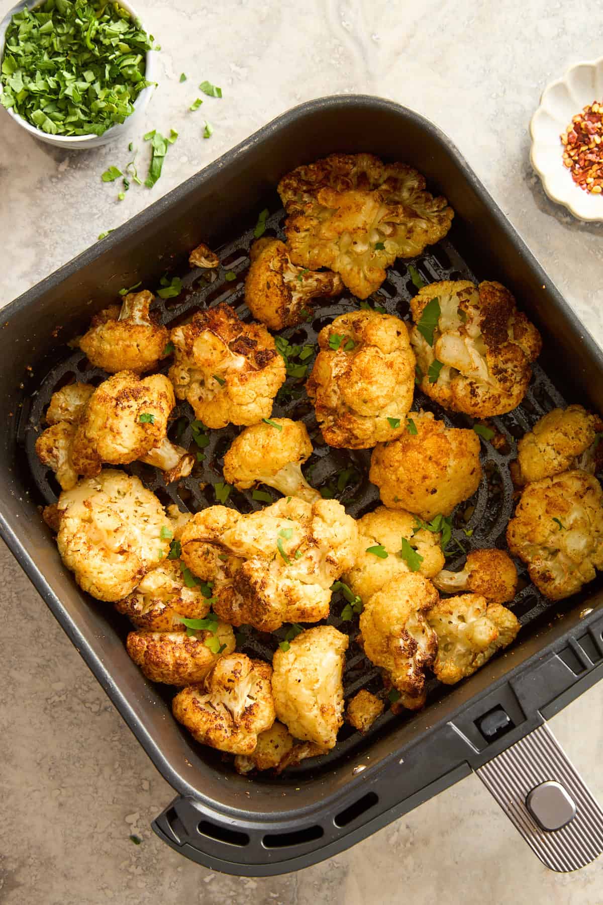 Roasted air fryer cauliflower in an air fryer basket.