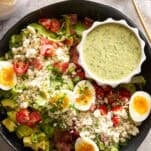 A Cobb salad with green goddess dressing on top.