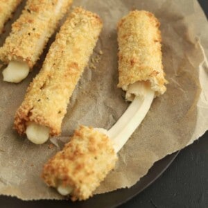 cheese sticks on parchment paper with one being pulled apart