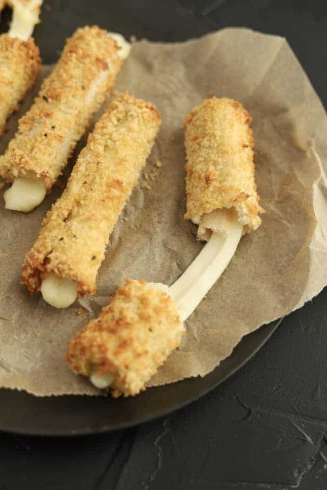 cheese sticks on parchment paper with one being pulled apart