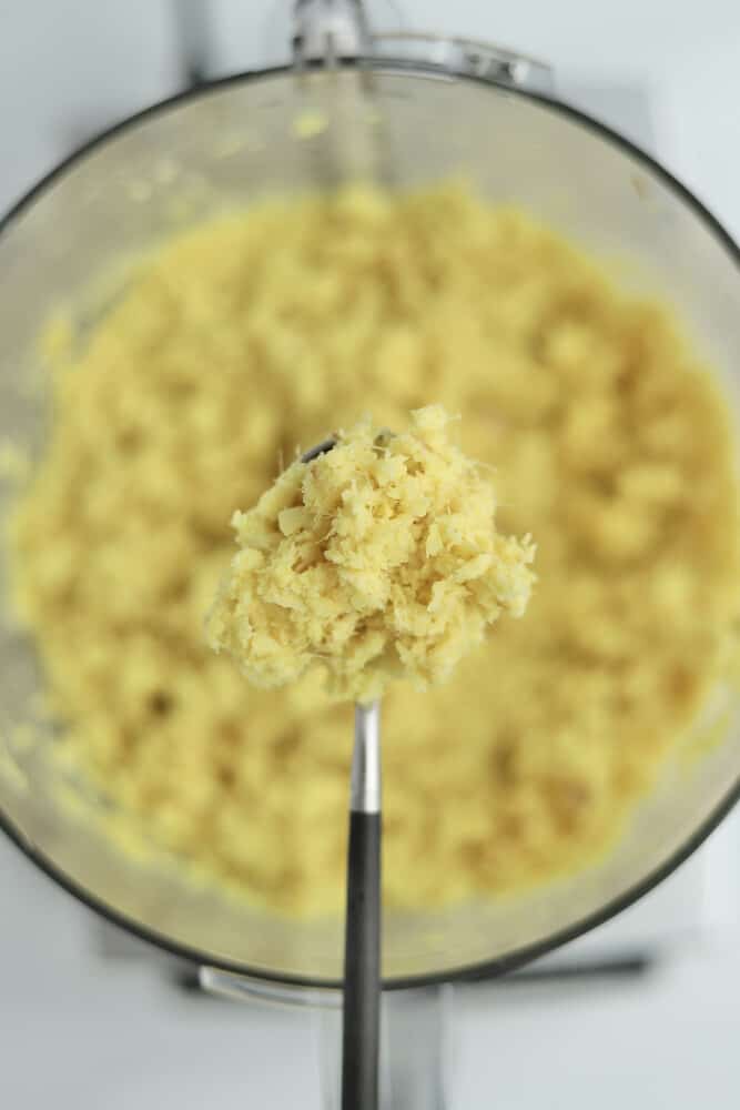 a spoonful of grated ginger root over a food processor of grated ginger.