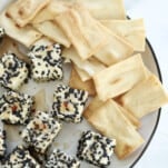 a plate of sesame crusted air fryer feta cubes with pita chips on the side
