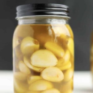 a mason jar full of garlic cloves submerged in oil