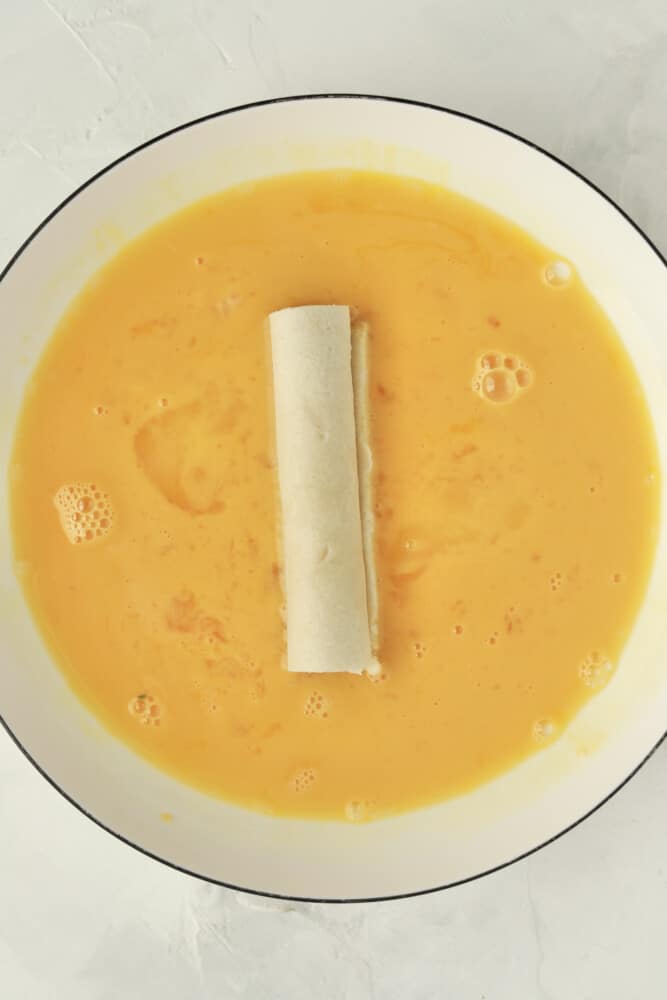 a cheese stick in a bowl of egg wash