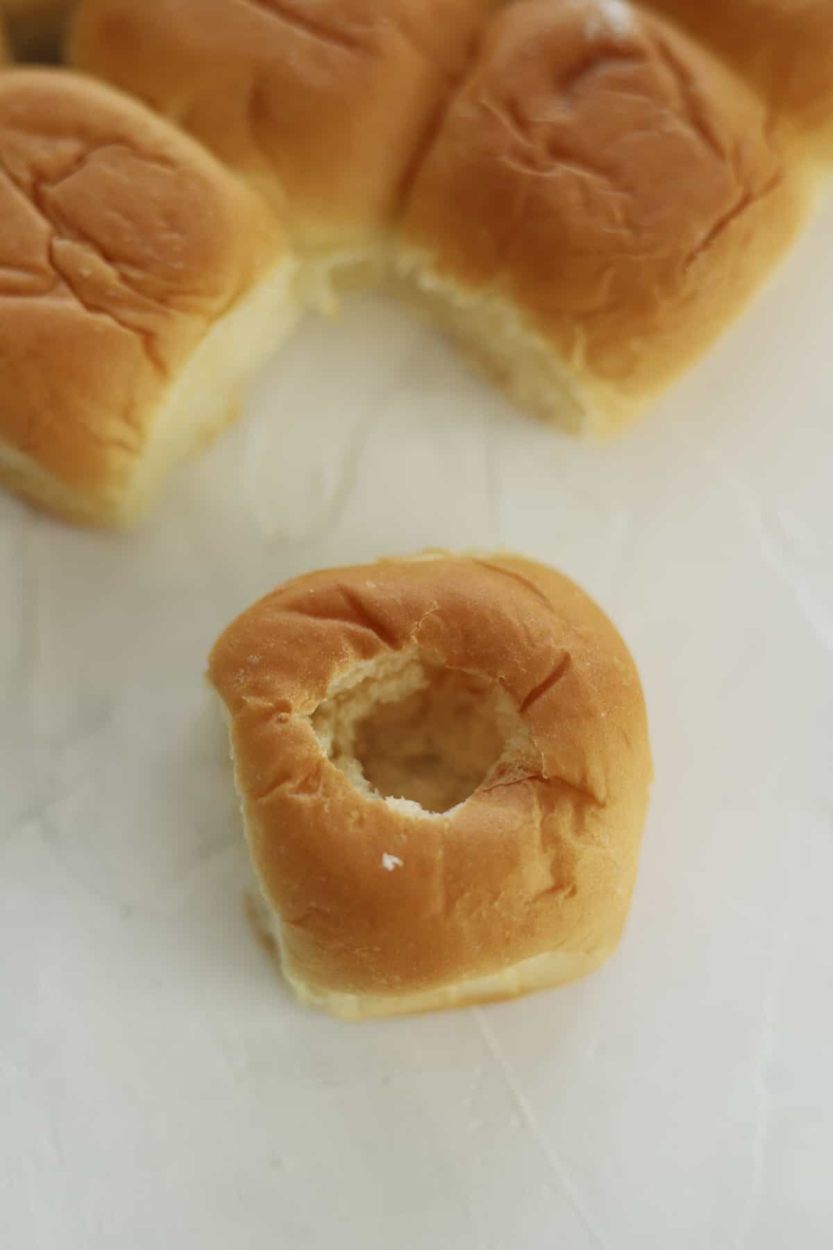 Hawaiian rolls, one with a hole poked into the center