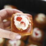 a hand holding an air fried strawberry cream cheese stuffed Hawaiian roll