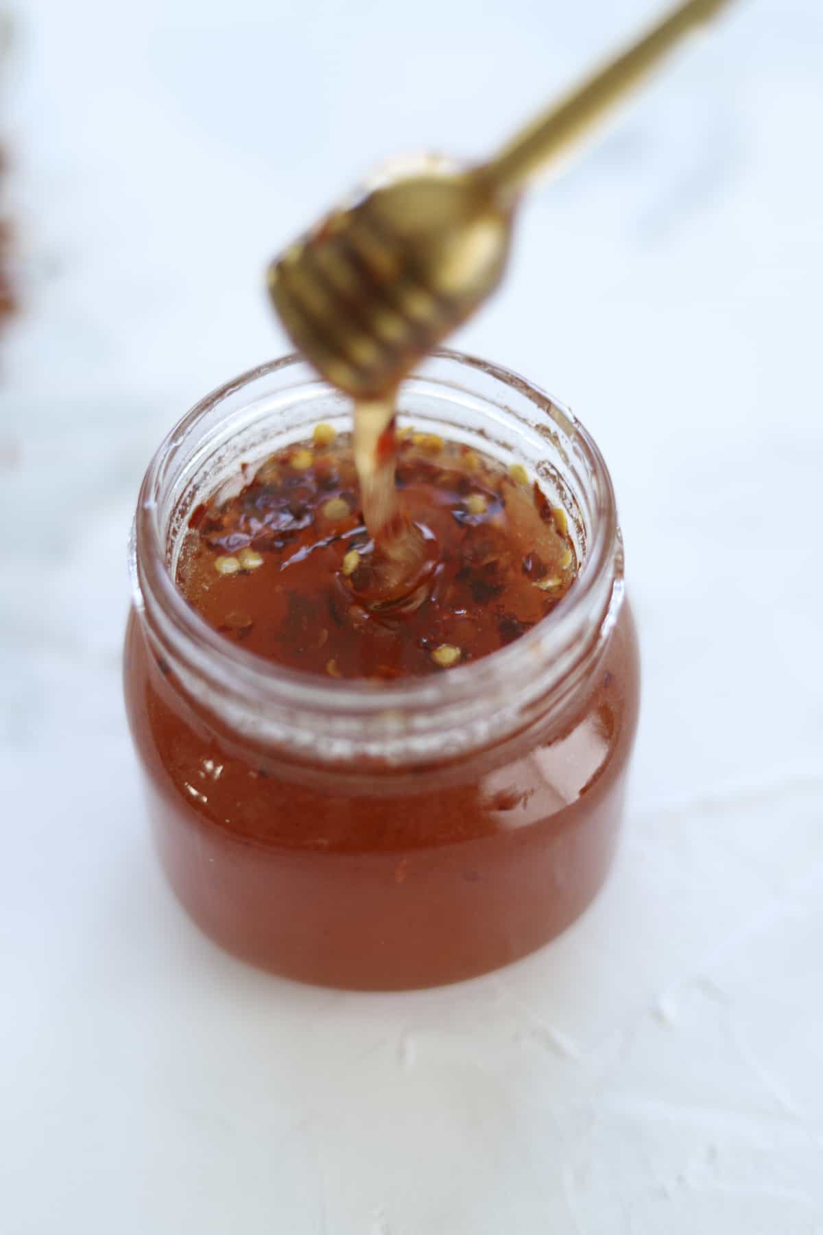 a honeycomb drizzling hot honey from a jar