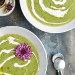 two bowls of zucchini soup topped with coconut milk.
