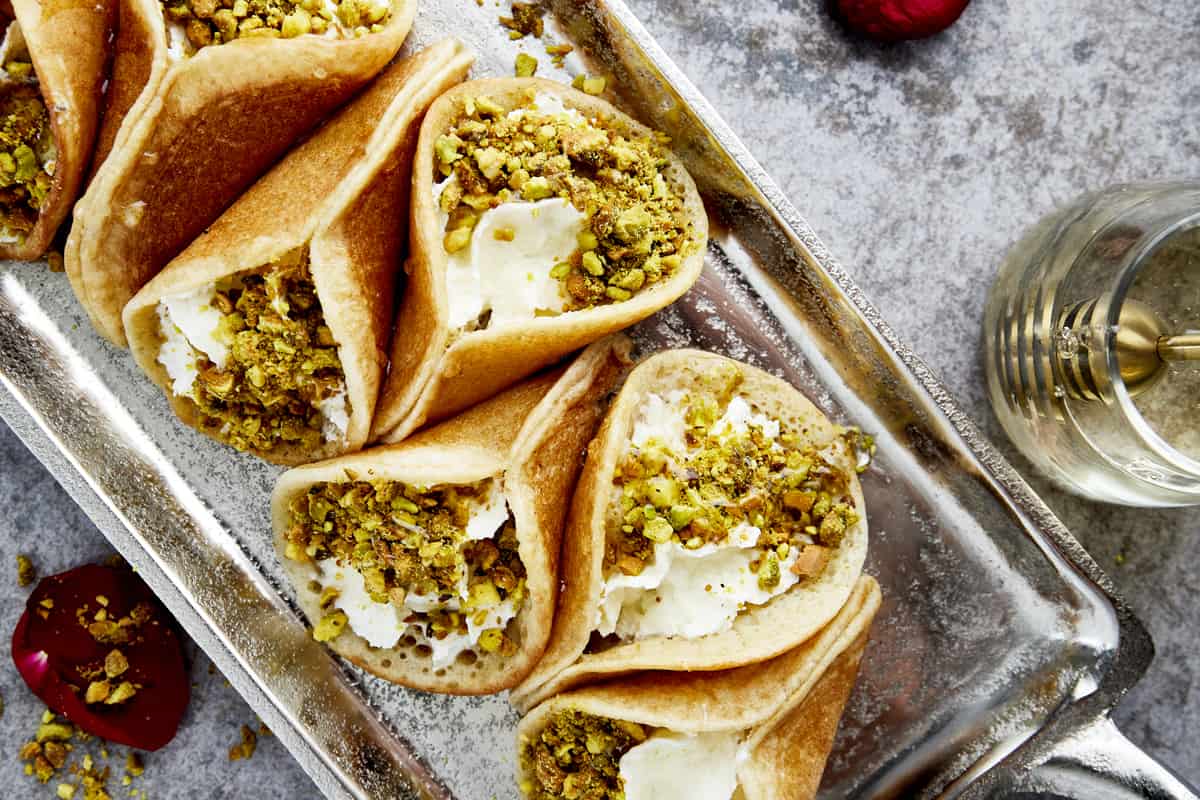 a platter of atayef with cream cheese and pistachios