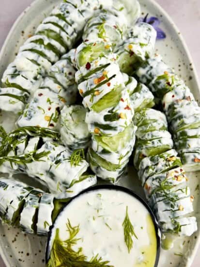 Spiraled cucumber yogurt salad with a bowl of yogurt sauce.