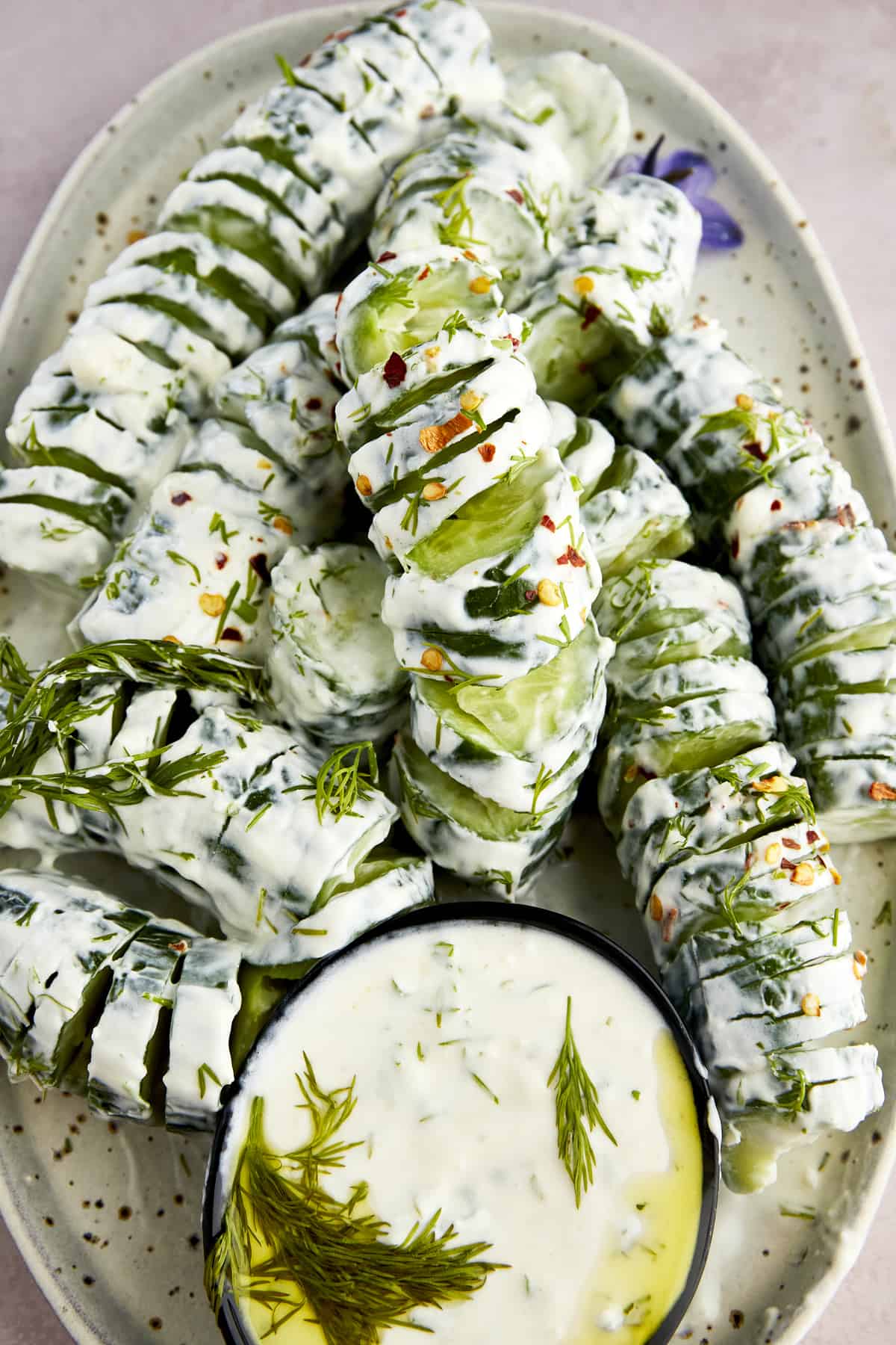 Spiraled cucumber yogurt salad with a bowl of yogurt sauce. 