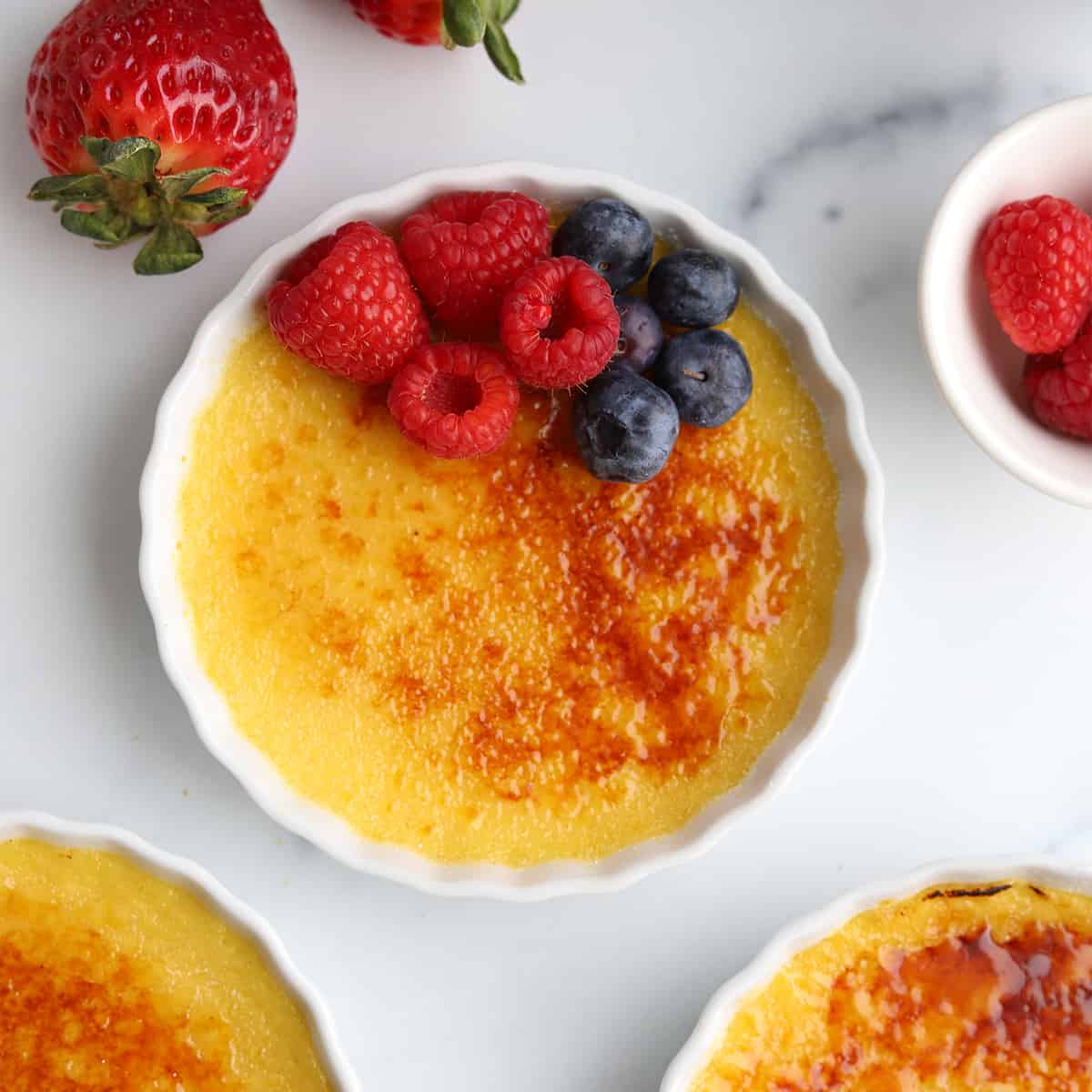 Overhead image of a pot of creme brulee topped with fresh berries.