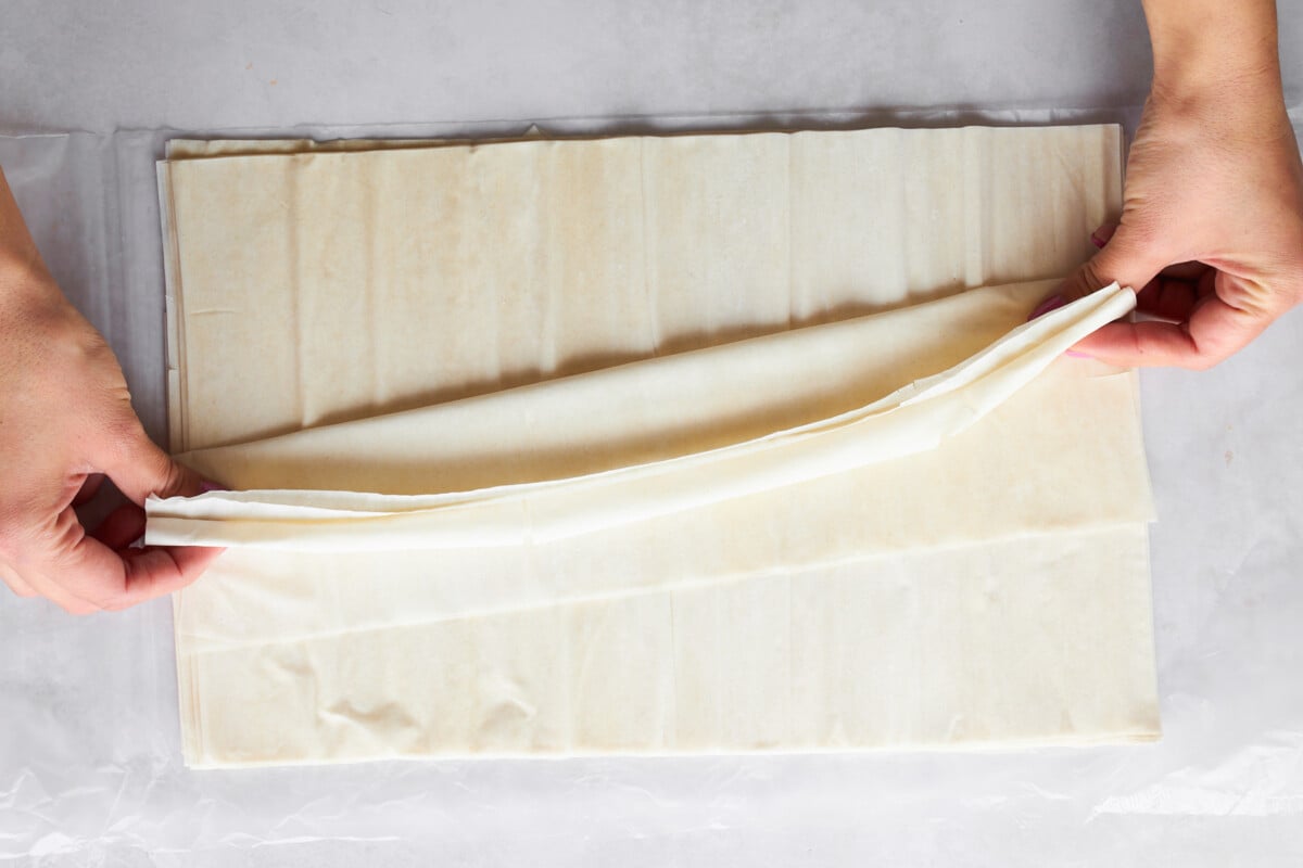 Raw phyllo dough being folded accordion-style.