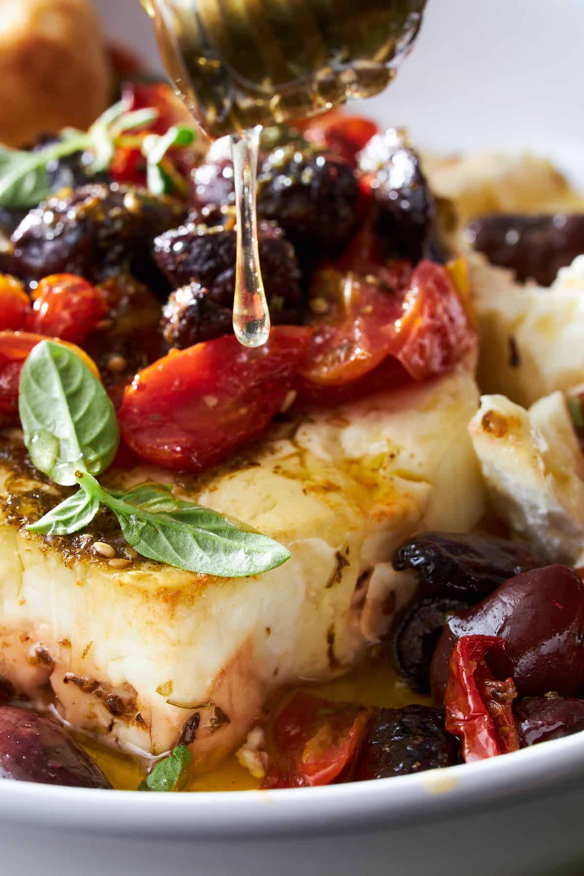 Honey being drizzled over Mediterranean baked feta dip.