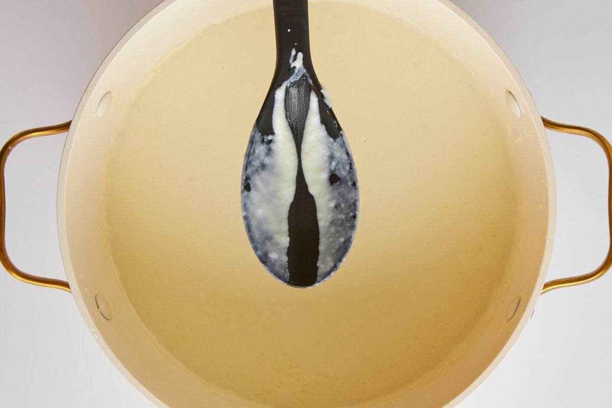 A spoon over a pot of bechamel sauce.