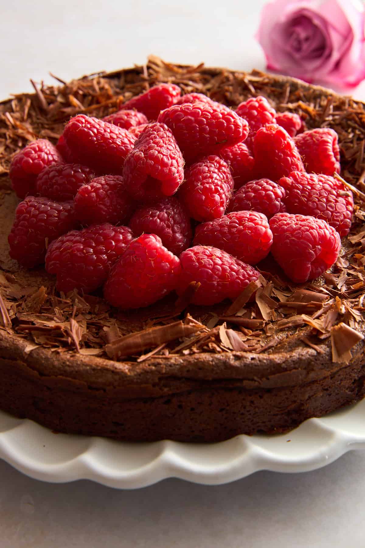 A flourless chocolate cake topped with chocolate shavings and raspberries.