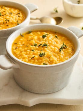 A ramekin of pastina soup topped with fresh rosemary.