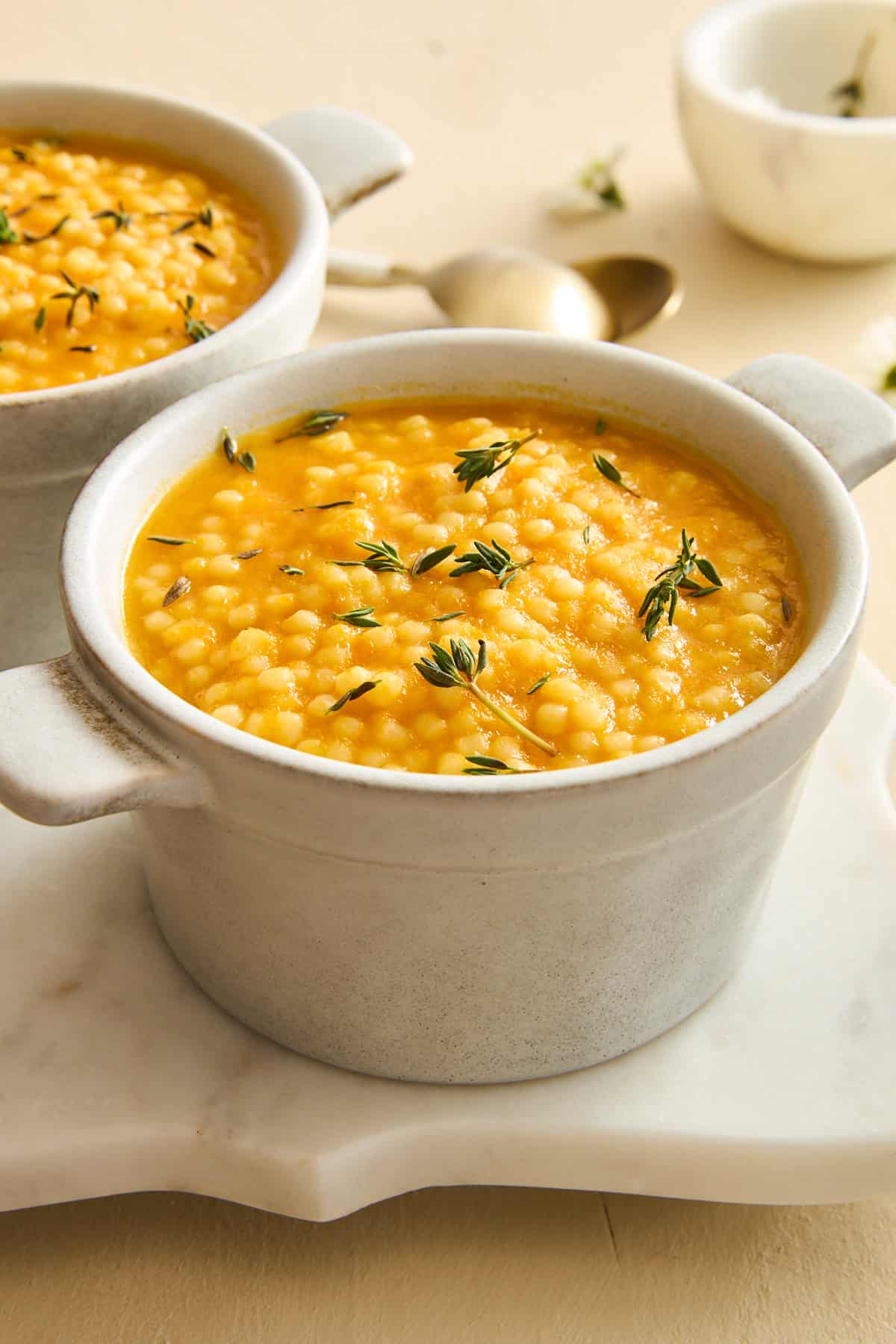 A ramekin of pastina soup topped with fresh rosemary. 