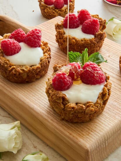Yogurt Filled Granola Cups topped with fresh raspberries and honey.