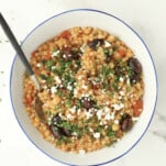 a bowl of one pot Greek couscous topped with feta and fresh herbs