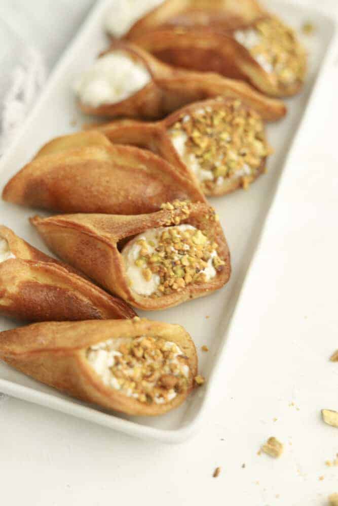 atayef on a plate with whipped cream and pistachios